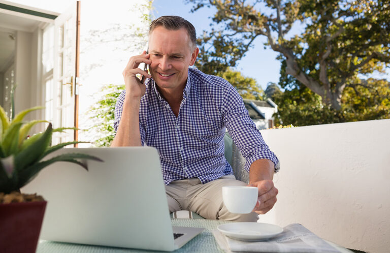 Businessman talking on phone while having coffee in outdoor cafe